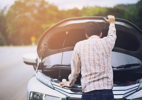man looking into the hood of a car